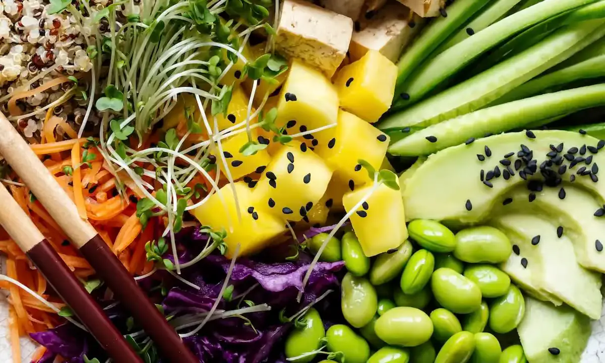 Colorful poke bowl vegetables: avocado, edamame, mango, carrots, purple cabbage, microgreens