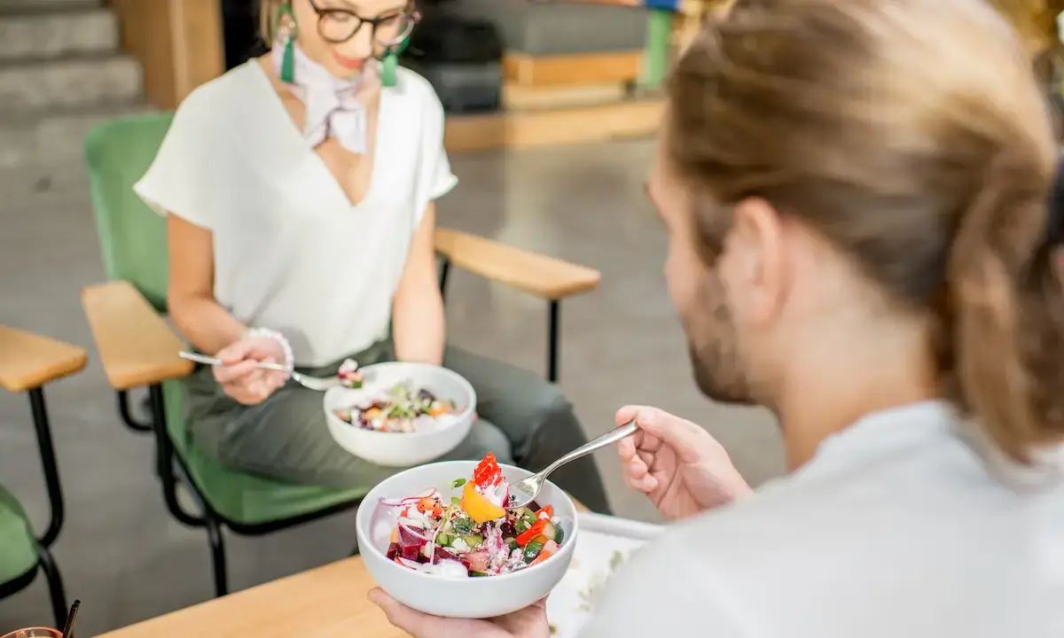 Two people eating customizable poke bowls with colorful toppings