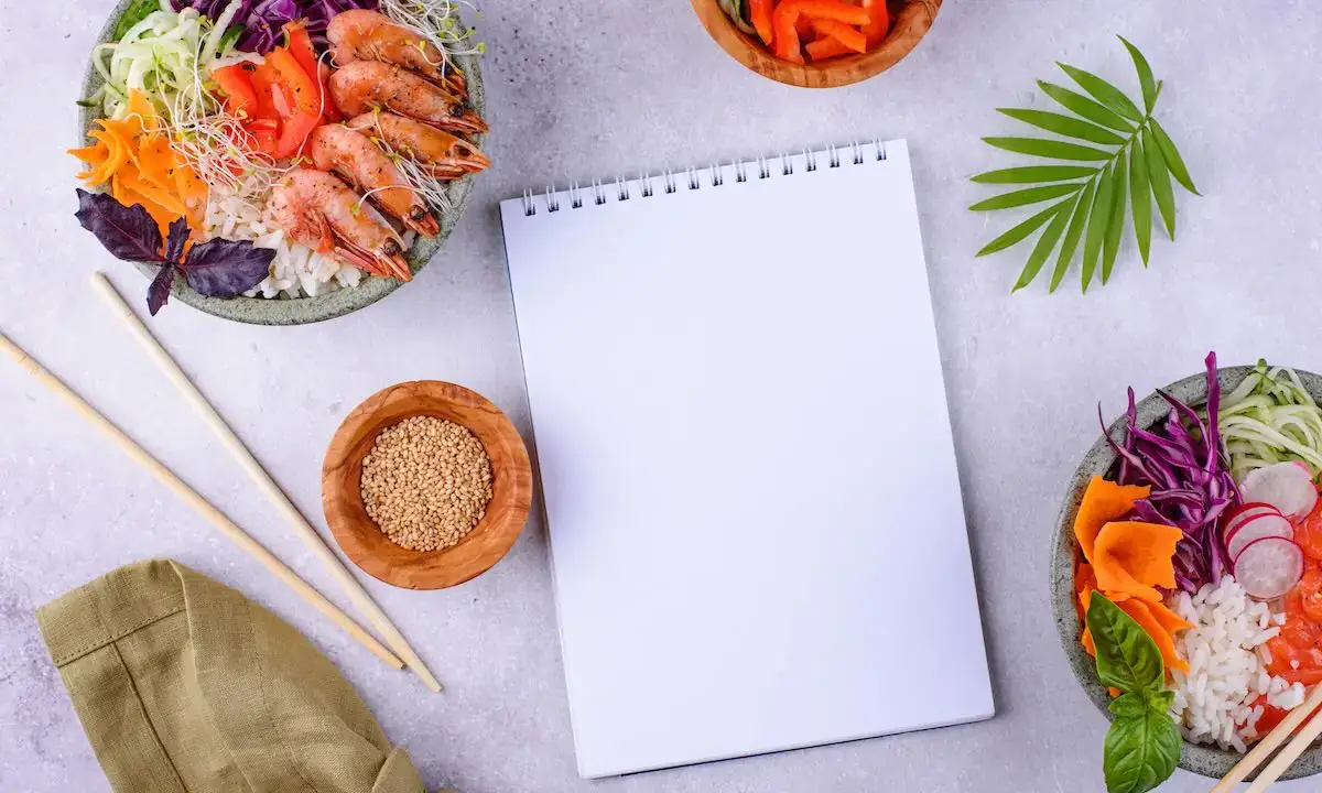 Blank spiral notepad for ingredient list surrounded by two poke bowls