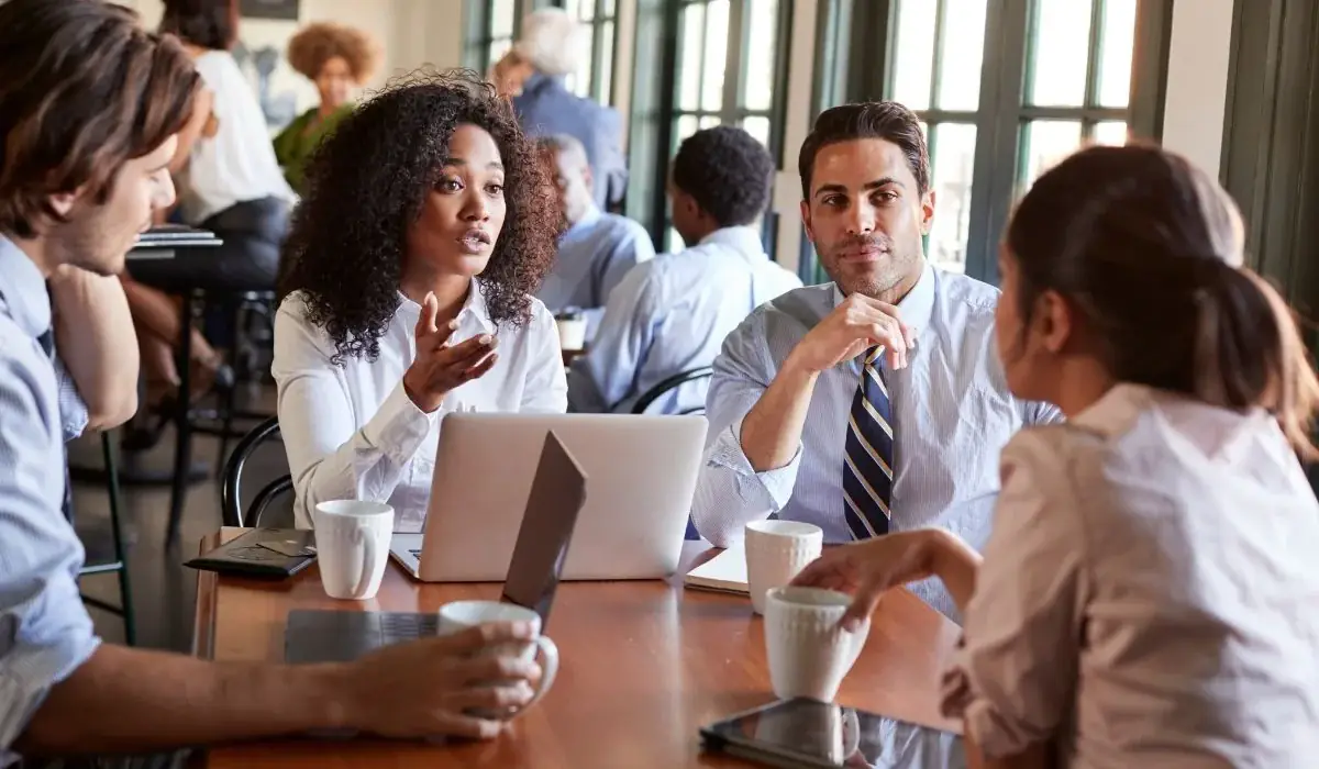 Group of professionals discussing franchise questions around a laptop and coffee