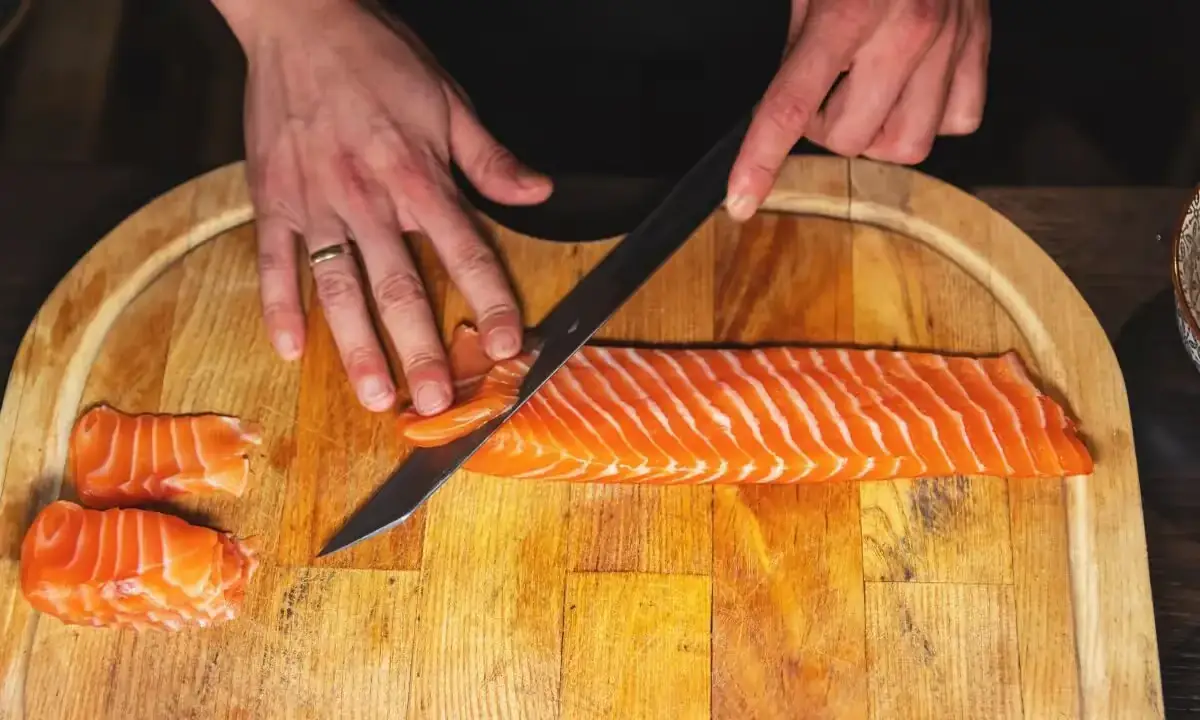 Frozen salmon fillet beside cooked salmon slices on plate
