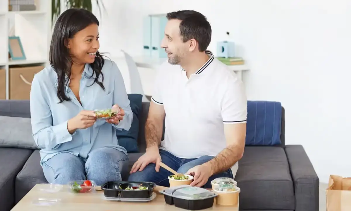 Couple on couch sharing poke bowls from takeout containers